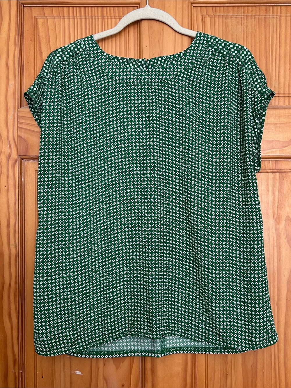 Ann Taylor green blouse features a white geometric pattern and a crewneck design